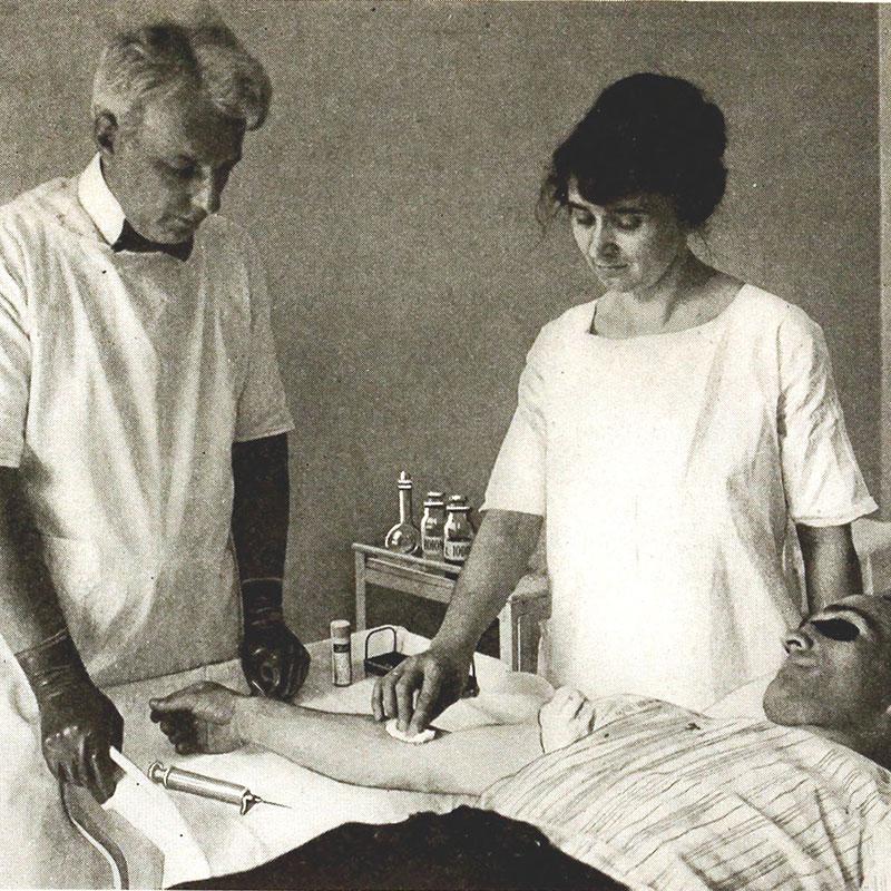 I begyndelsen af 1900-tallet blev kviksølvbehandling af syfilis afløst af ekstremt smertefulde injektioner med den antibakterielle arsenikforbindelse salvarsan. Fra 1912 anvendtes det knap så giftige neosalvarsan, evt. kombineret med kviksølvindgnidning. Behandlingen virkede, men blev afskaffet, da penicillin i slutningen af 1940’erne kom på markedet. Behandling med neosalvarsan ved amerikansk hospital i 1920. Foto: The Library of Congress.